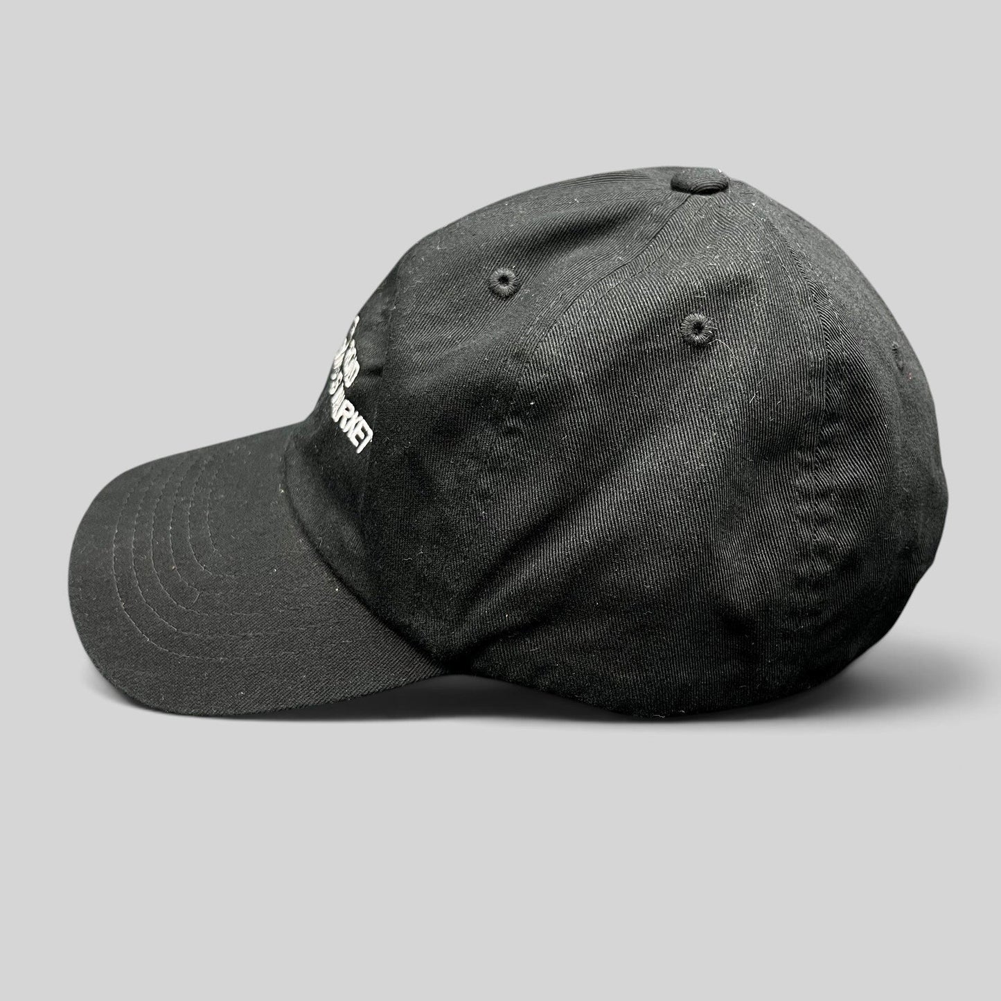 Raree Finds black cotton strapback dad cap with white Silk Road Anonymous Market embroidery, side profile view.