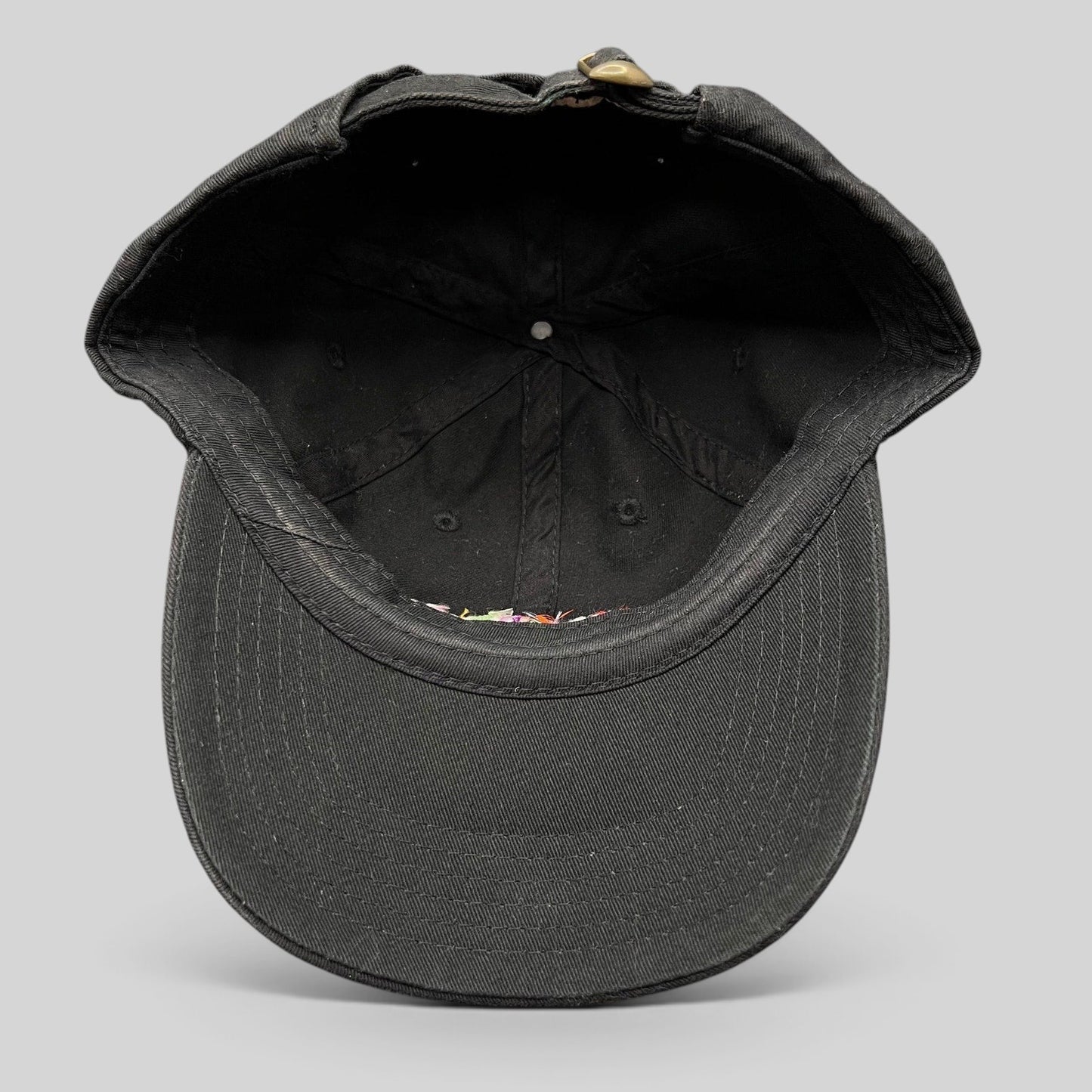 Raree Finds black cotton strapback hat interior view showing the adjustable metal slider and curved brim construction.