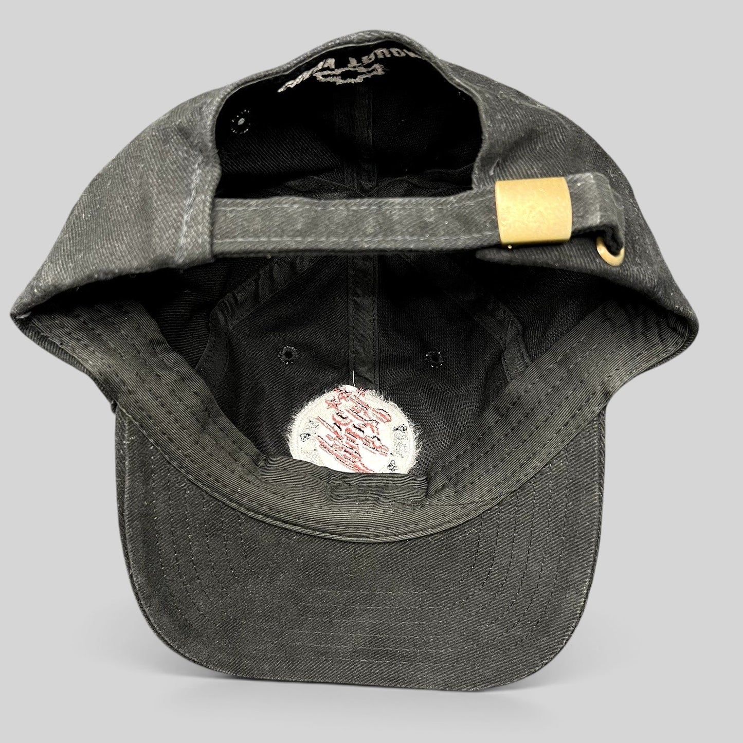 Raree Finds black cotton strapback hat with adjustable brass buckle, showing interior construction and branding.