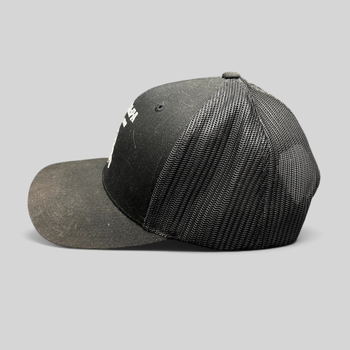 Raree Finds black Yupoong trucker snapback hat with The Talpa Est. 1962 embroidered cactus logo, side profile view.