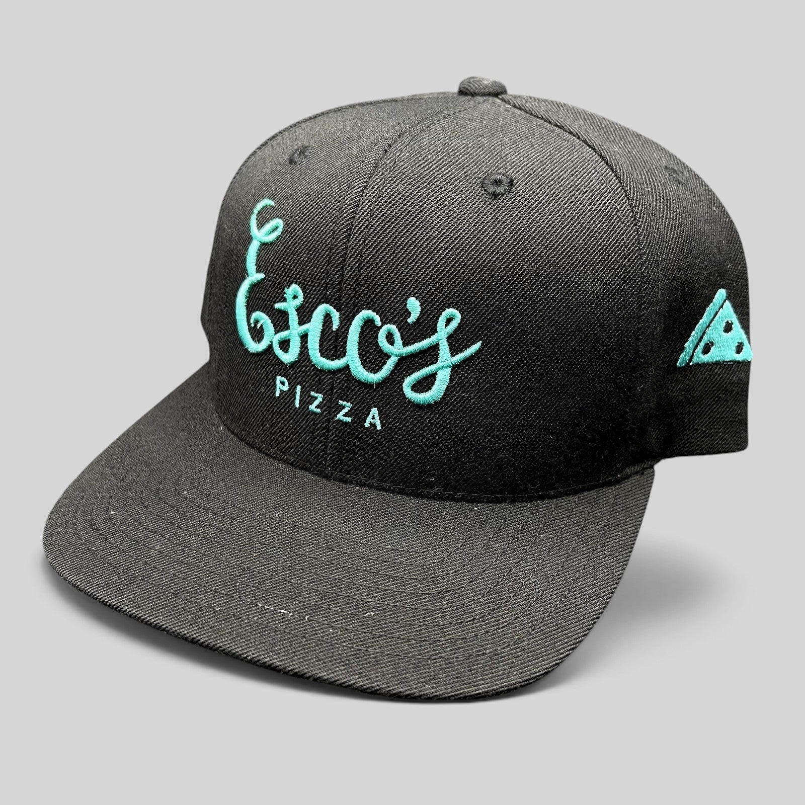 Raree Finds black snapback hat with teal Esco’s Pizza script embroidery and a pizza slice detail on the side.