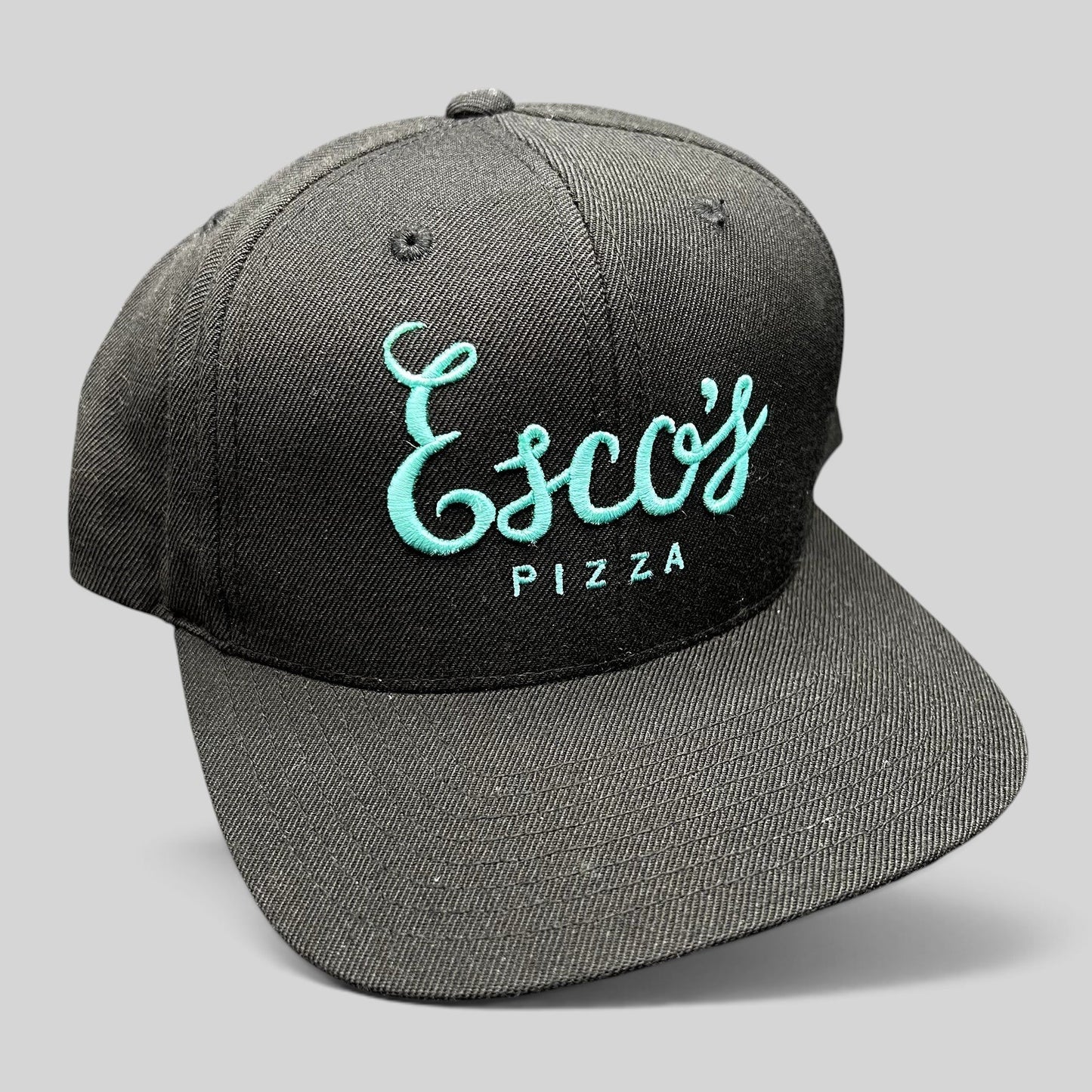 Raree Finds black snapback hat with teal Esco’s Pizza script embroidery on the front and a flat brim.