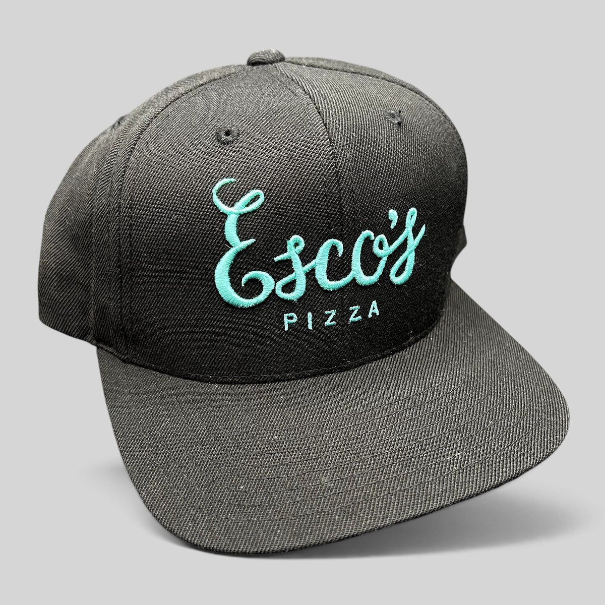 Raree Finds black snapback hat with teal Esco’s Pizza script embroidery on the front and a flat brim.