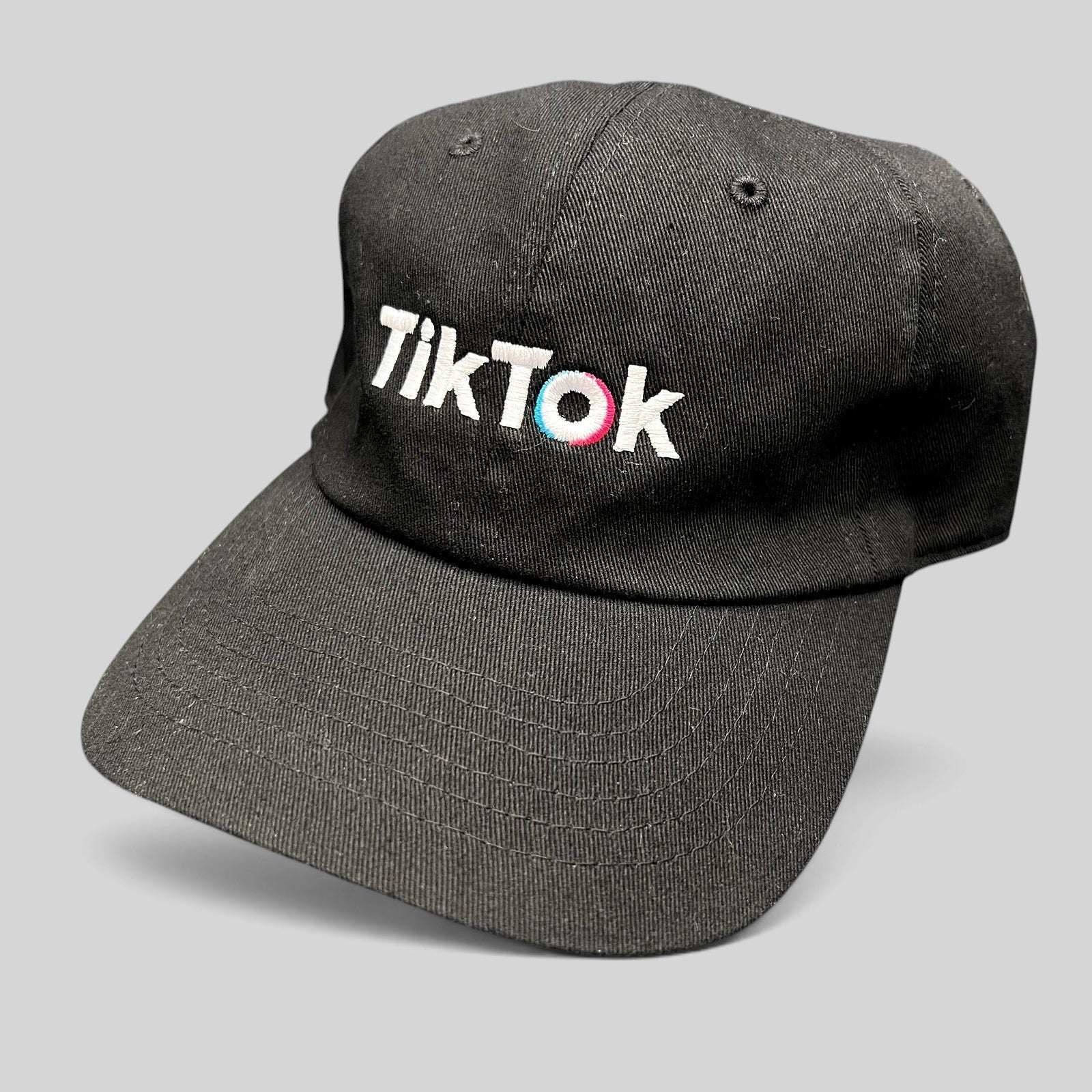 Raree Finds black cotton dad cap with embroidered TikTok logo in white, teal, and pink on an unstructured crown.