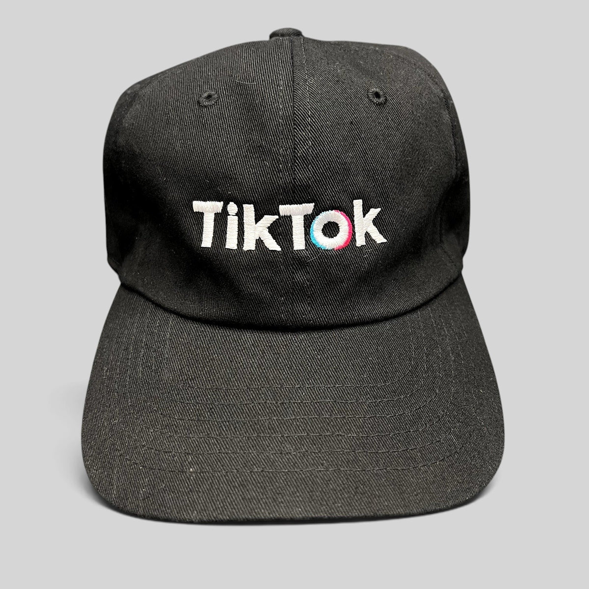 Raree Finds black TikTok dad cap with white embroidered logo and teal and pink accent stitching on a curved brim hat.