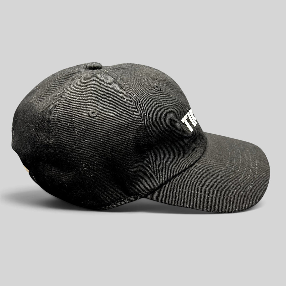 Raree Finds black cotton dad cap with embroidered white TikTok logo and curved brim, side profile view.