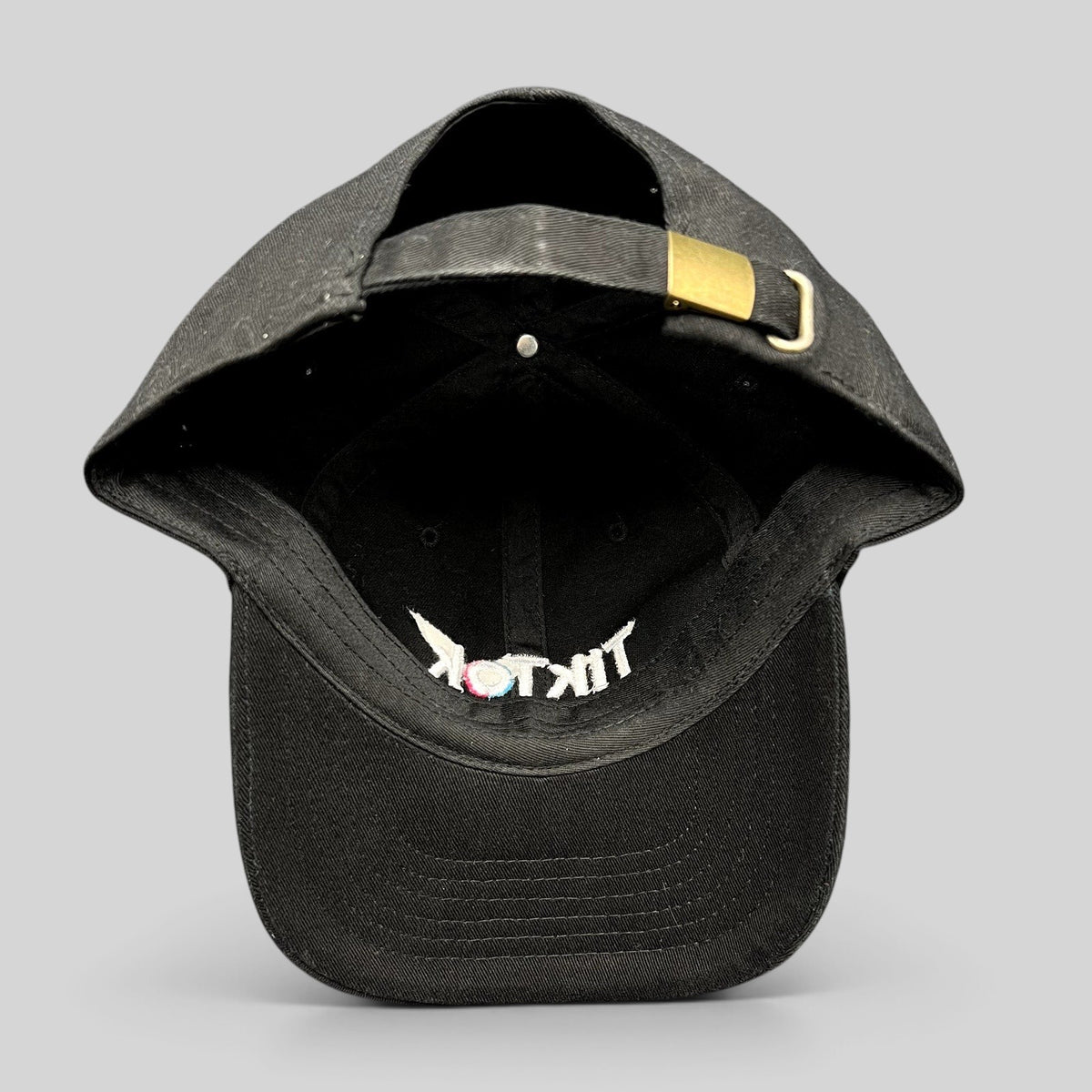 Raree Finds black TikTok dad cap with adjustable strapback closure, metal buckle, and embroidered logo on the brim.