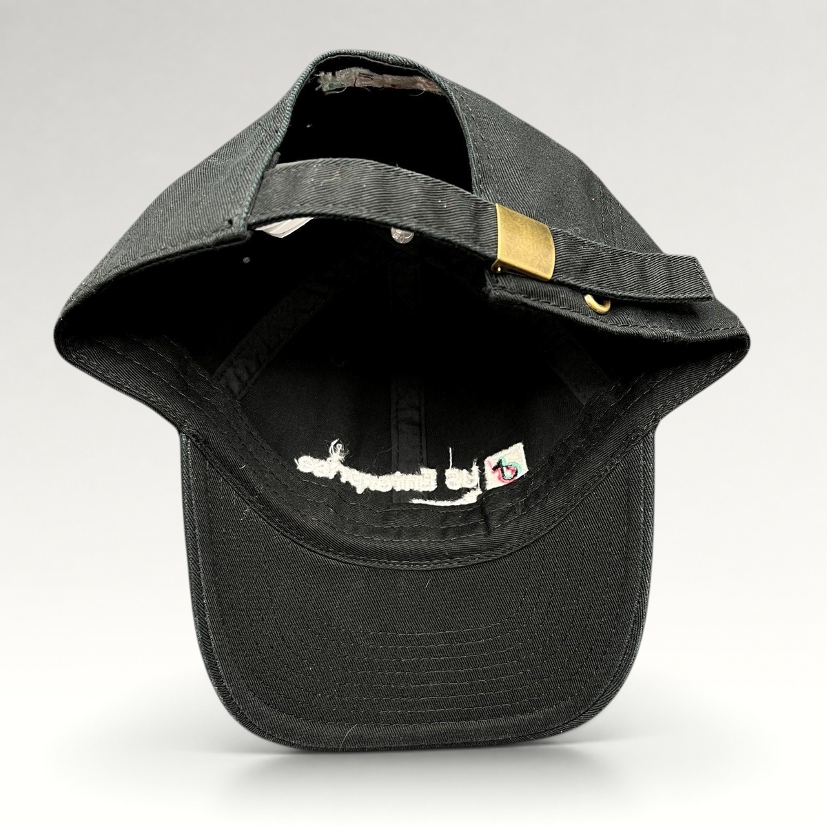 Raree Finds black TikTok strapback hat showing the interior, adjustable strap, and brass buckle hardware.