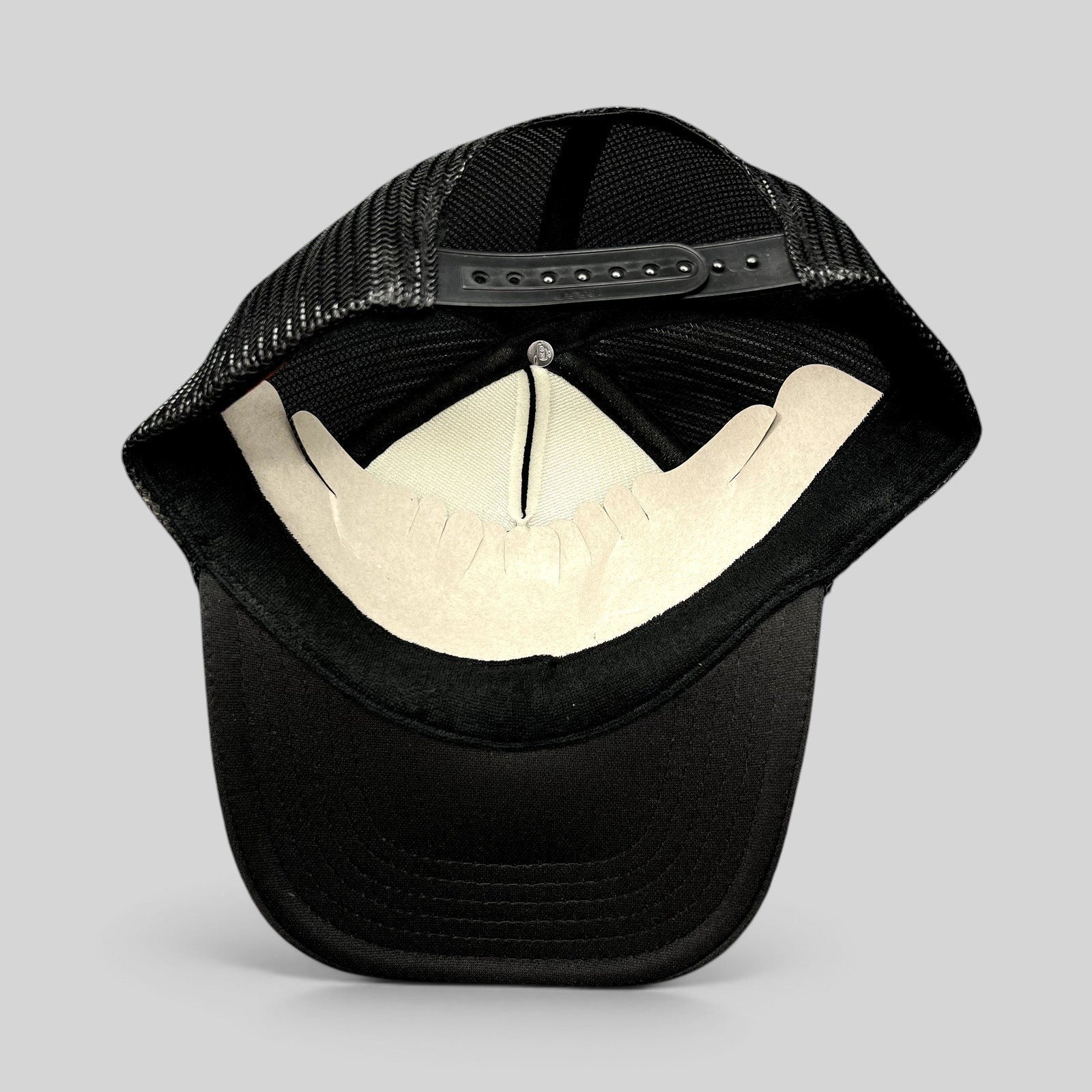 Raree Finds black Otto trucker hat interior view showing mesh back panels, foam front lining, and snapback closure.