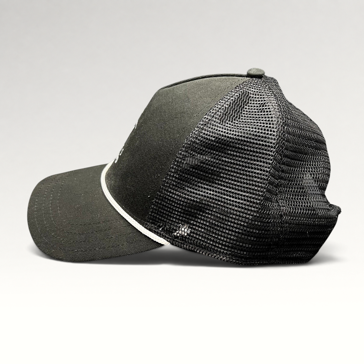Raree Finds black trucker hat with breathable mesh back, white rope detail, and curved bill from Discovery Collection.