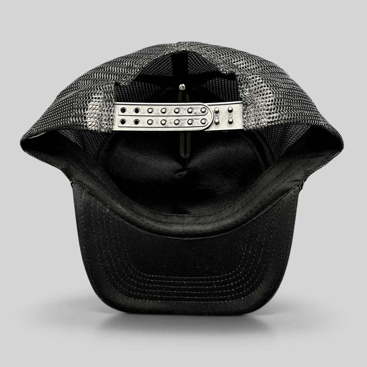 Raree Finds vintage black mesh trucker hat showing the adjustable plastic snapback closure and interior construction.