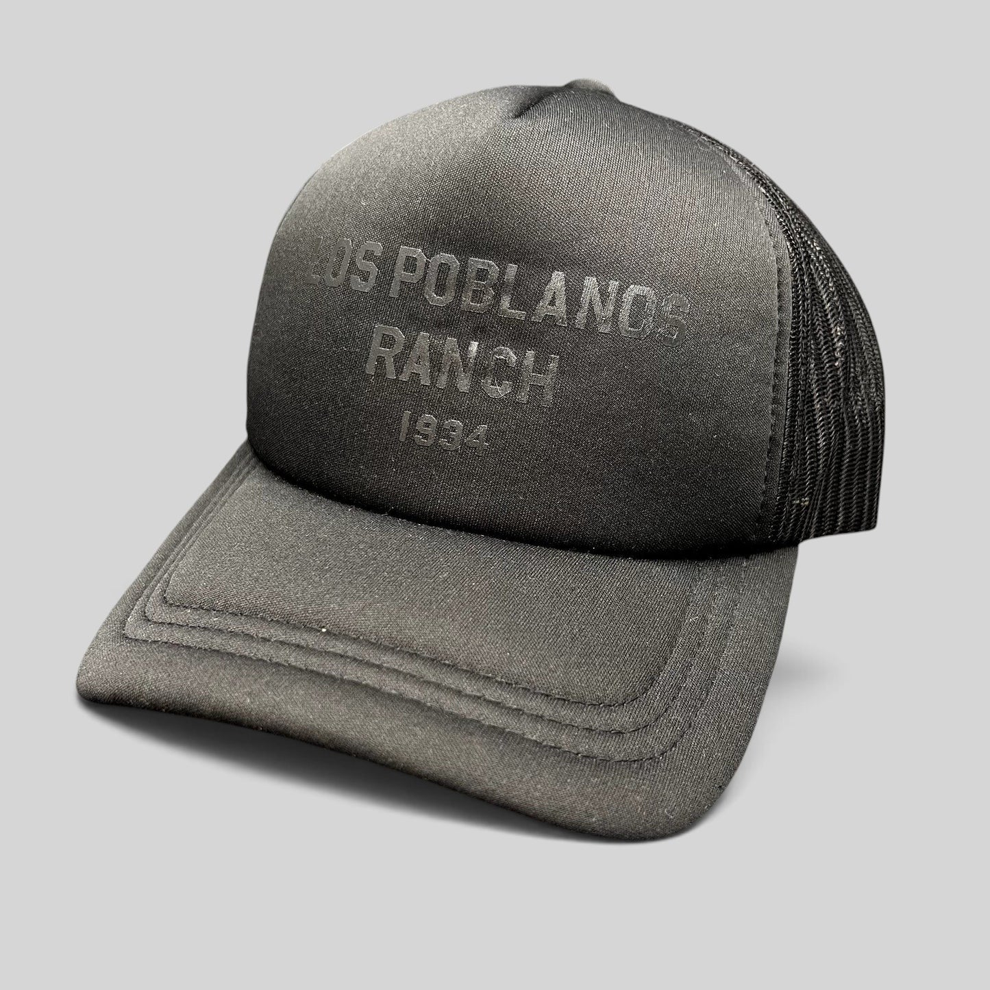 Raree Finds Los Poblanos Ranch 1934 black foam trucker hat with tonal front graphic, mesh back, and snapback closure.