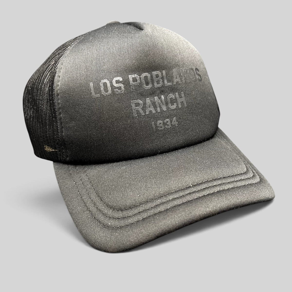 Raree Finds Los Poblanos Ranch 1934 black foam trucker hat with mesh back, curved brim, and tonal front branding.