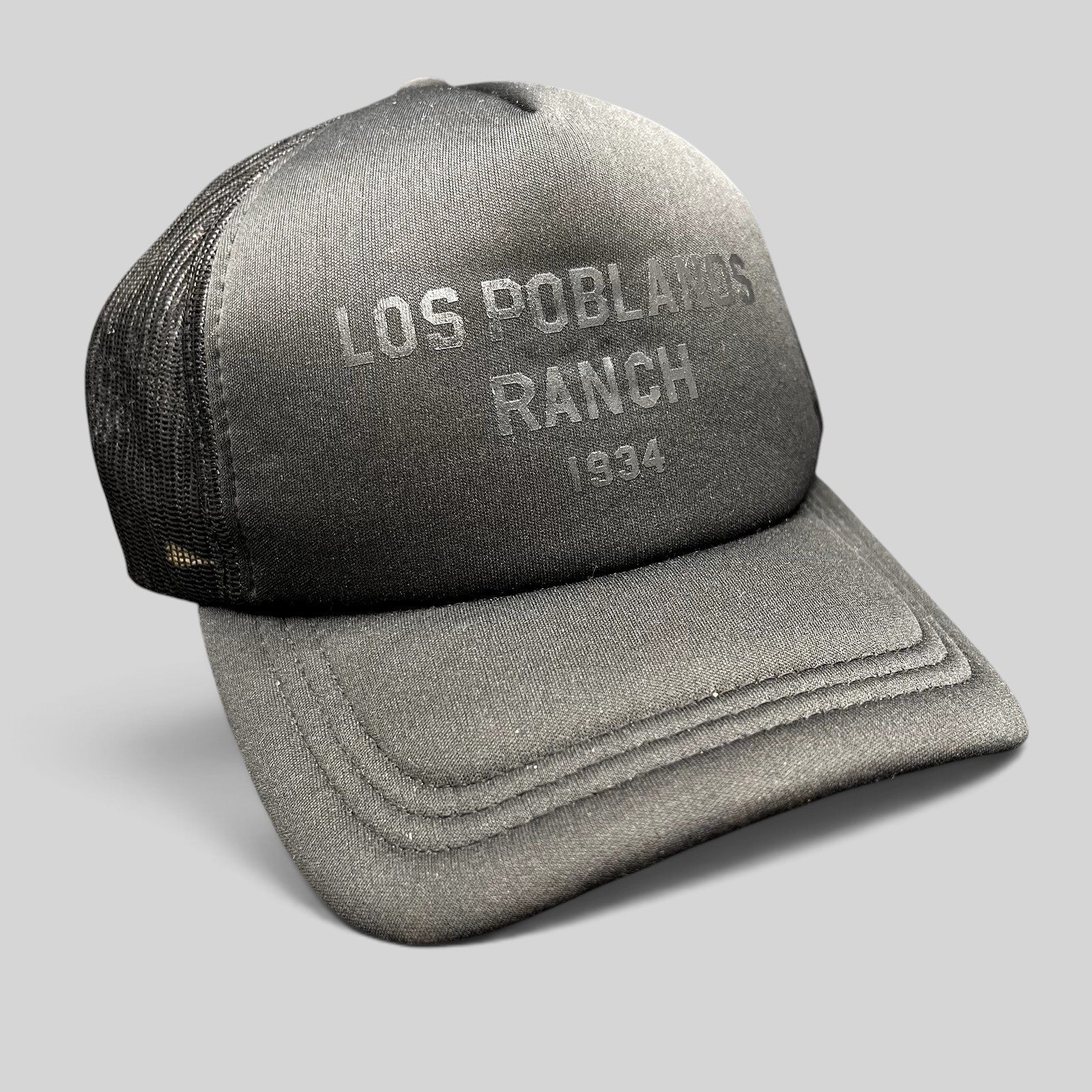 Raree Finds Los Poblanos Ranch 1934 black foam trucker hat with mesh back, curved brim, and tonal front branding.