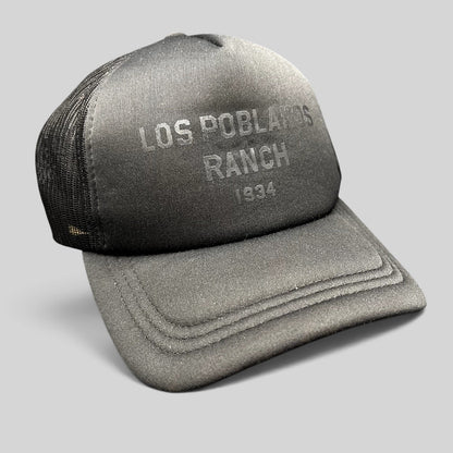Raree Finds Los Poblanos Ranch 1934 black foam trucker hat with mesh back, curved brim, and tonal front branding.