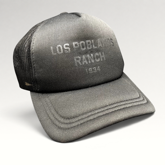 Raree Finds Los Poblanos Ranch 1934 black foam trucker hat with mesh back, curved brim, and tonal front branding.