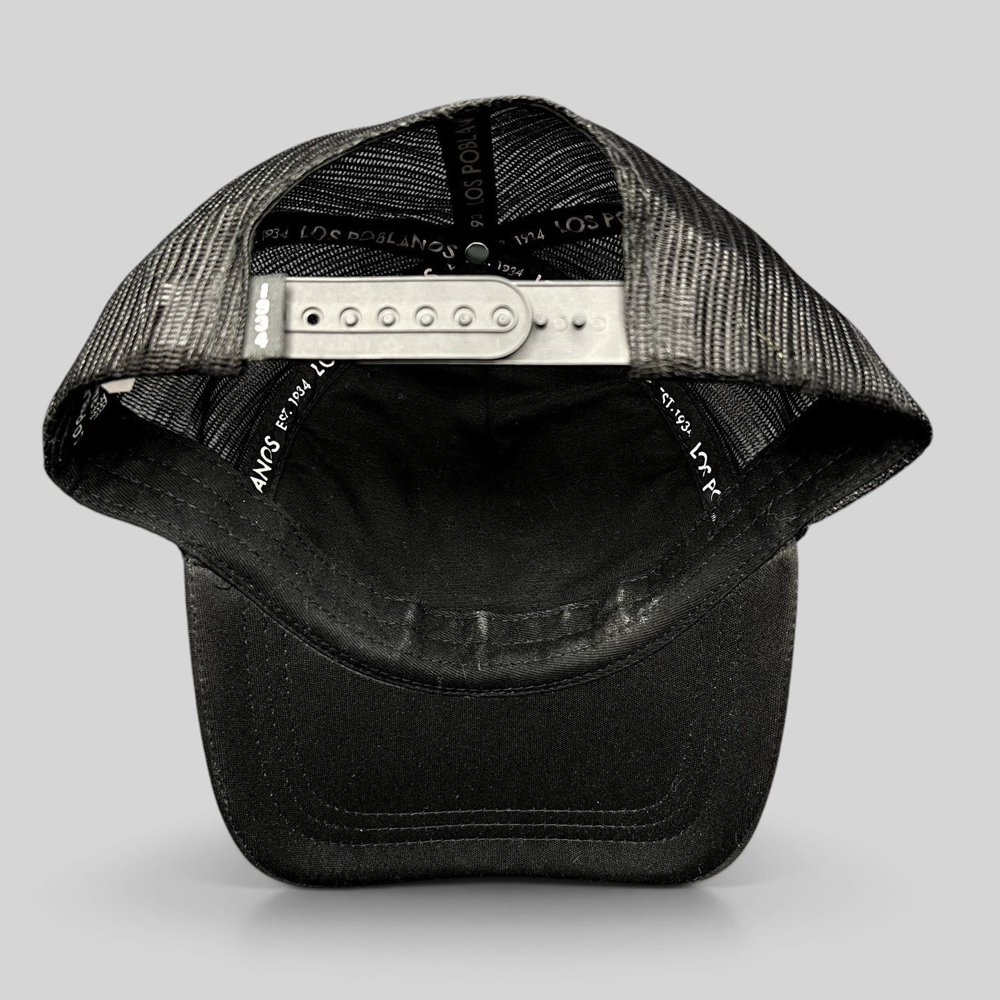 Raree Finds black trucker hat with mesh back, curved brim, and adjustable snapback closure showing interior branding.