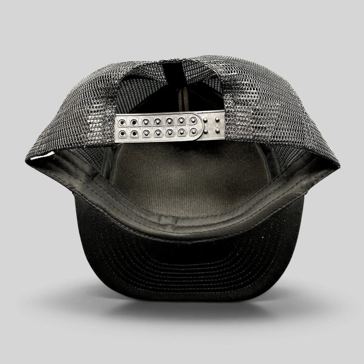Raree Finds black trucker snapback hat showing the adjustable plastic strap and breathable mesh back panel