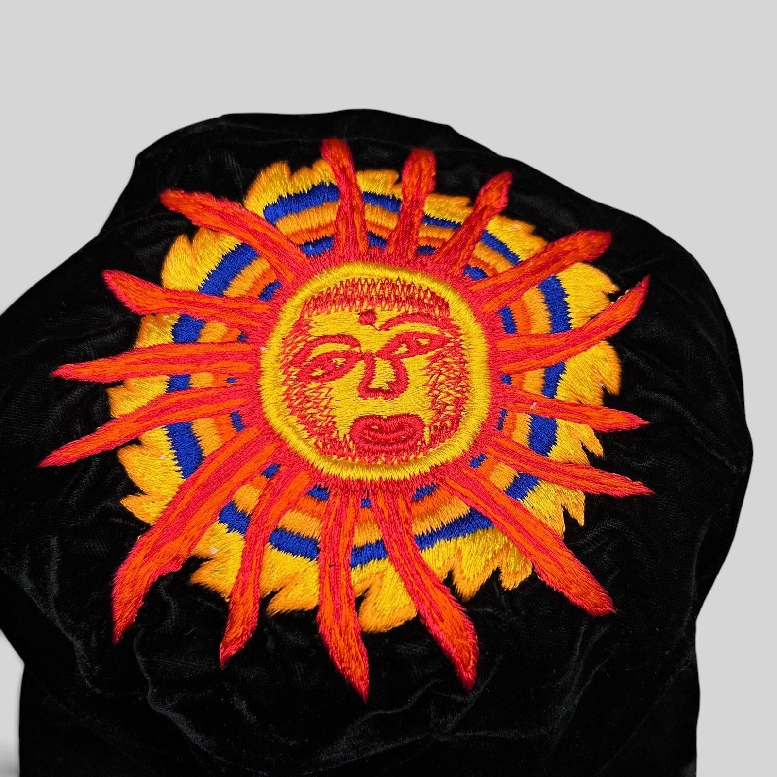 Raree Finds vintage black velvet cap featuring a vibrant embroidered southwestern sun face in red, yellow, and blue.