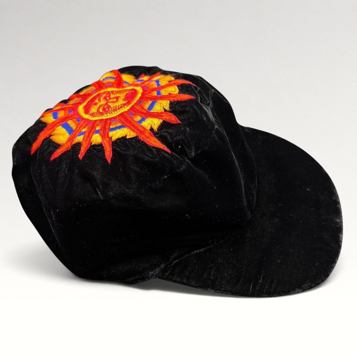 Raree Finds vintage black velvet cap featuring a colorful embroidered southwestern sun face motif on the crown.