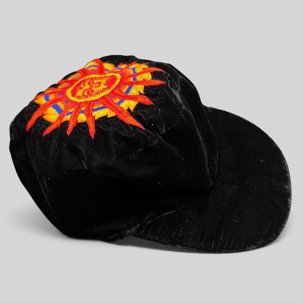 Raree Finds vintage black velvet cap featuring a colorful embroidered southwestern sun face motif on the crown.