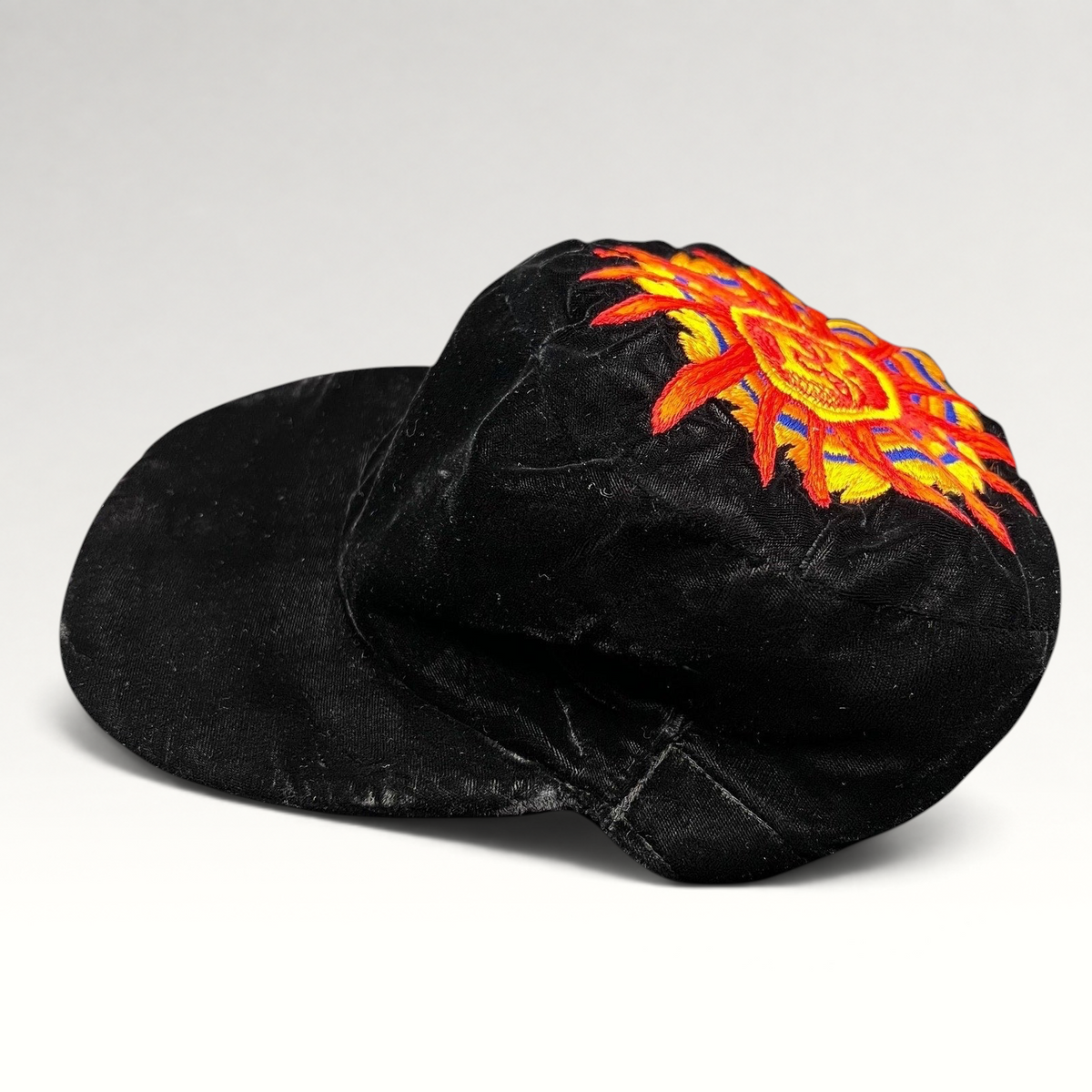 Raree Finds vintage Unicas Southwest black velvet cap with a colorful embroidered sun face motif on the crown.