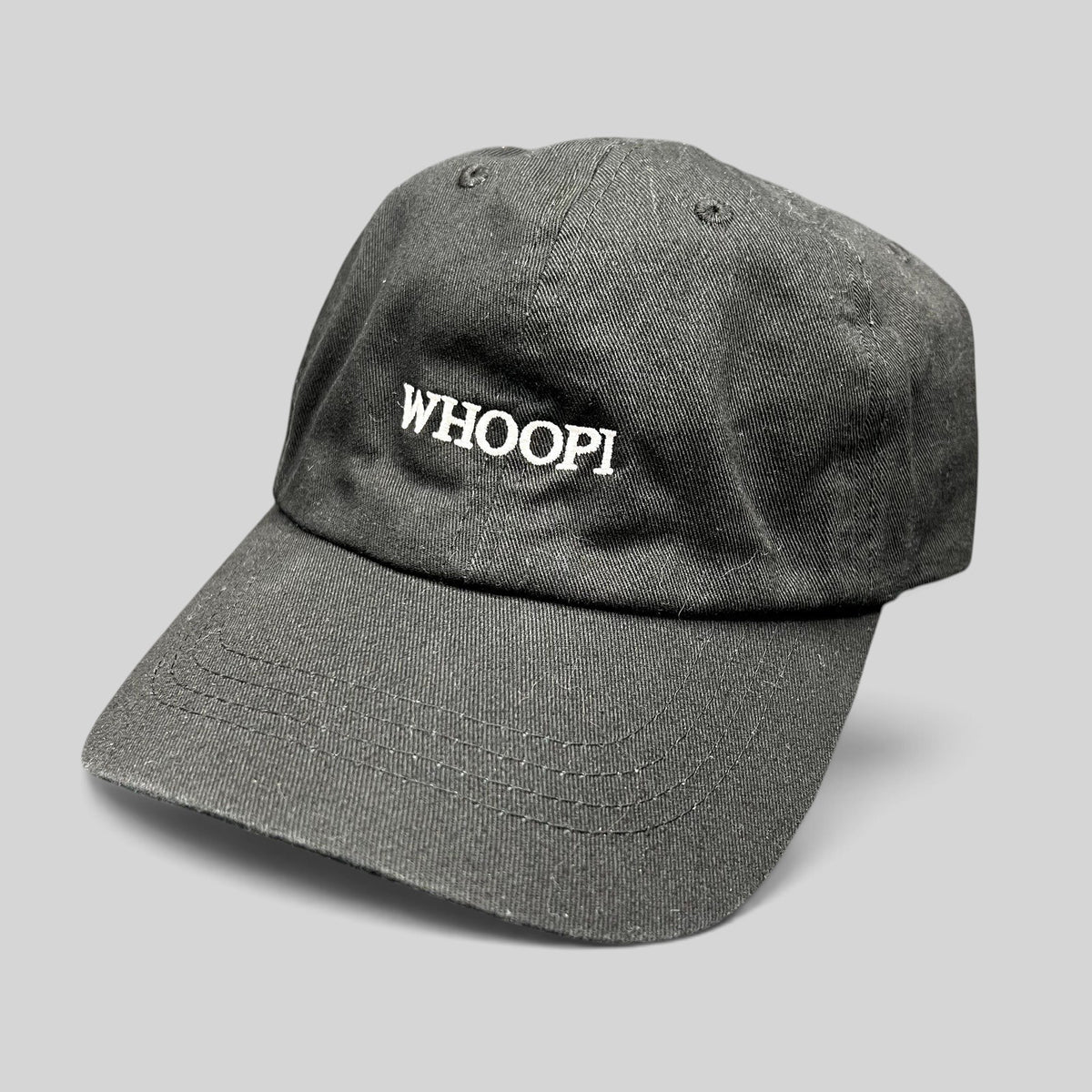 Raree Finds black organic cotton dad cap with white WHOOPI embroidery on the front and a curved brim.