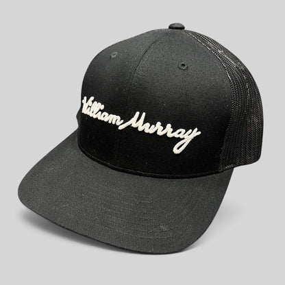 Raree Finds black William Murray Golf trucker hat with white script logo embroidery and mesh back panels