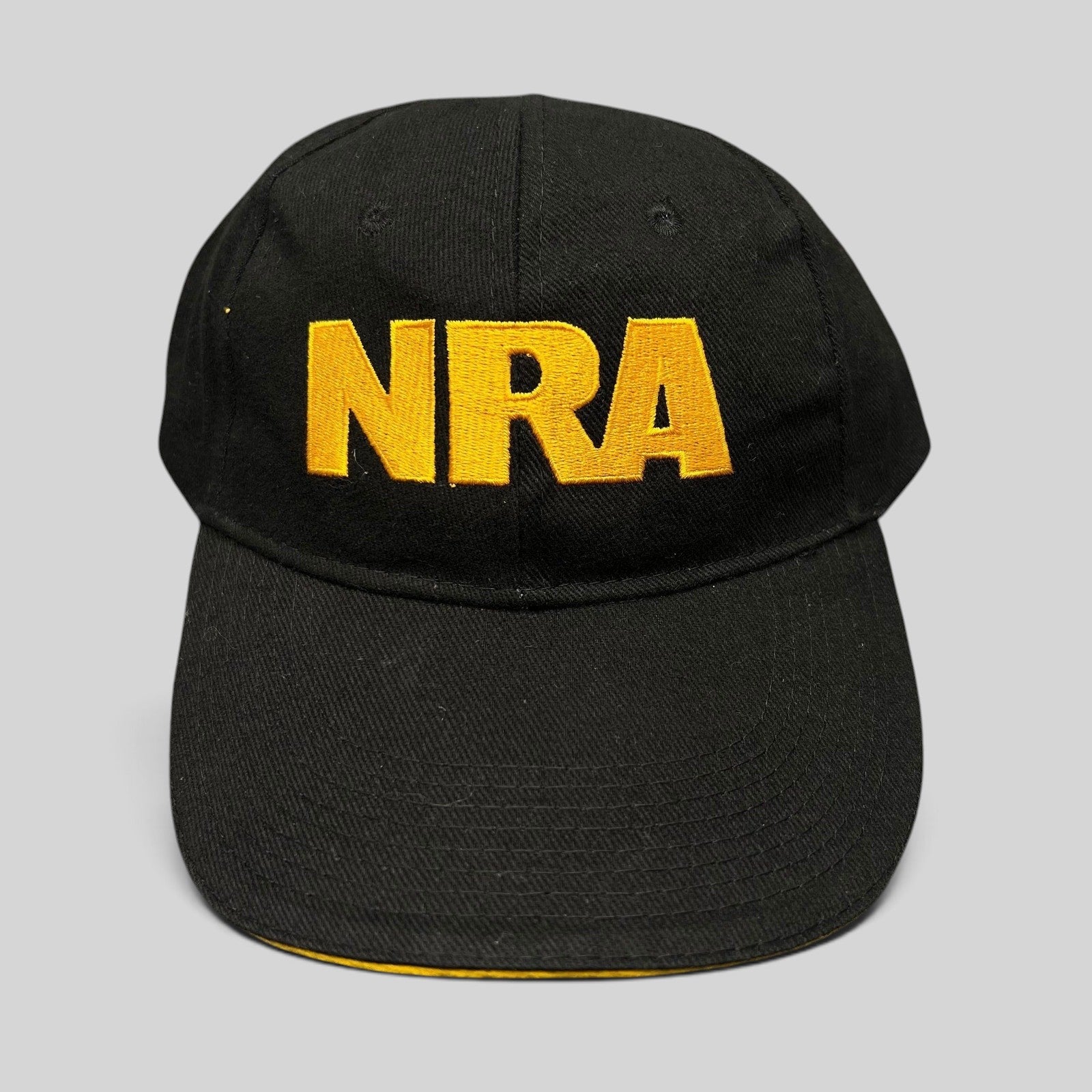 Raree Finds black strapback hat with bold yellow embroidered NRA lettering on the front and a curved brim