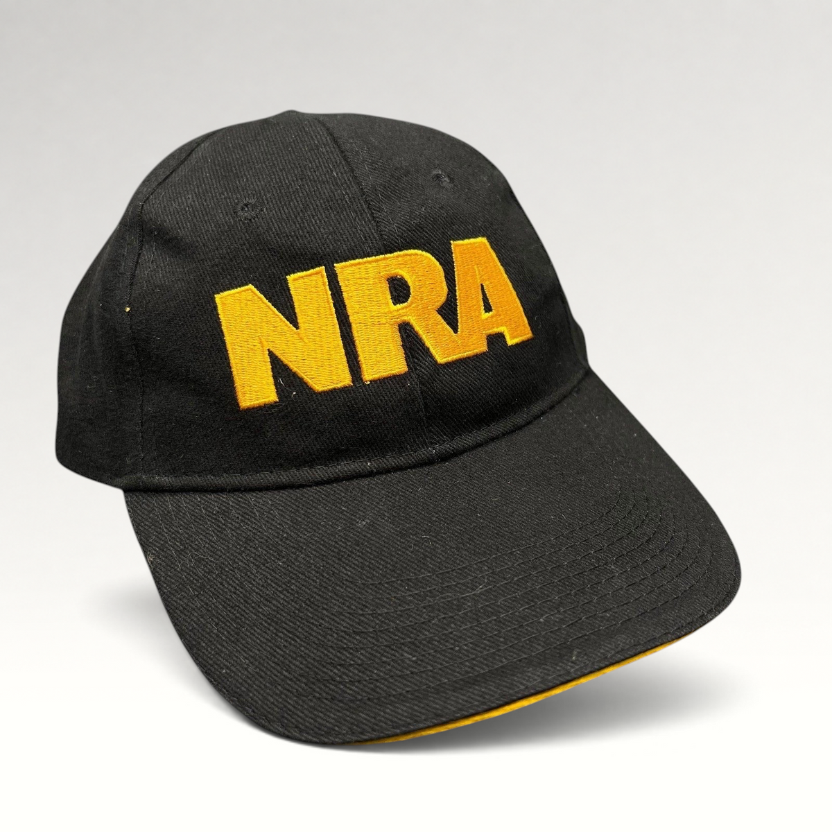 Raree Finds black strapback hat with bold yellow embroidered NRA lettering on the front and a curved brim