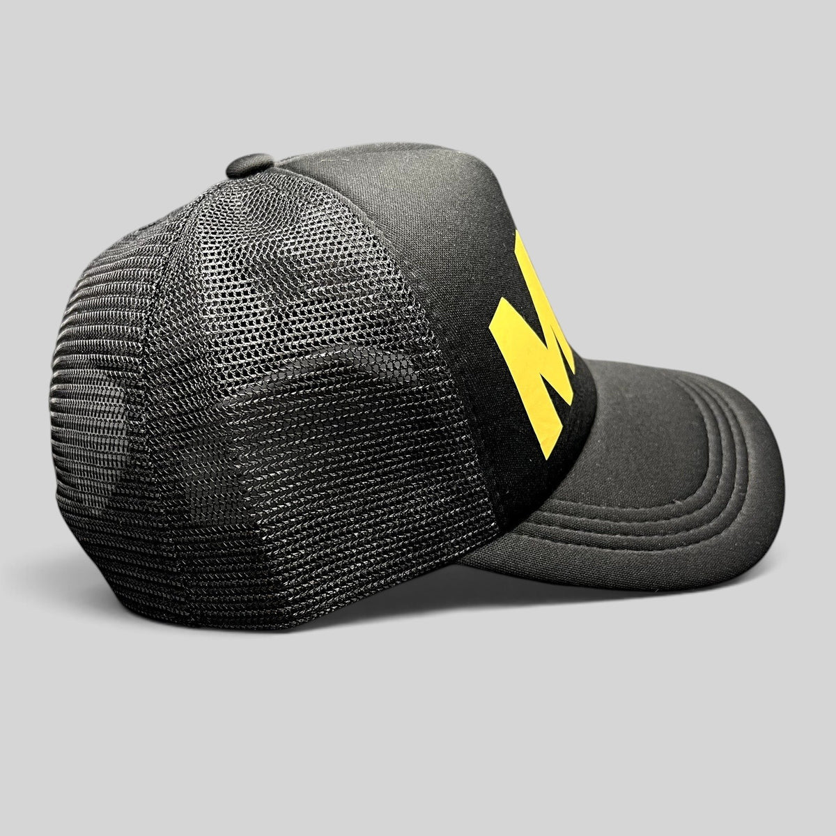 Raree Finds black foam trucker hat with yellow Milo logo and mesh back panels, side profile view.