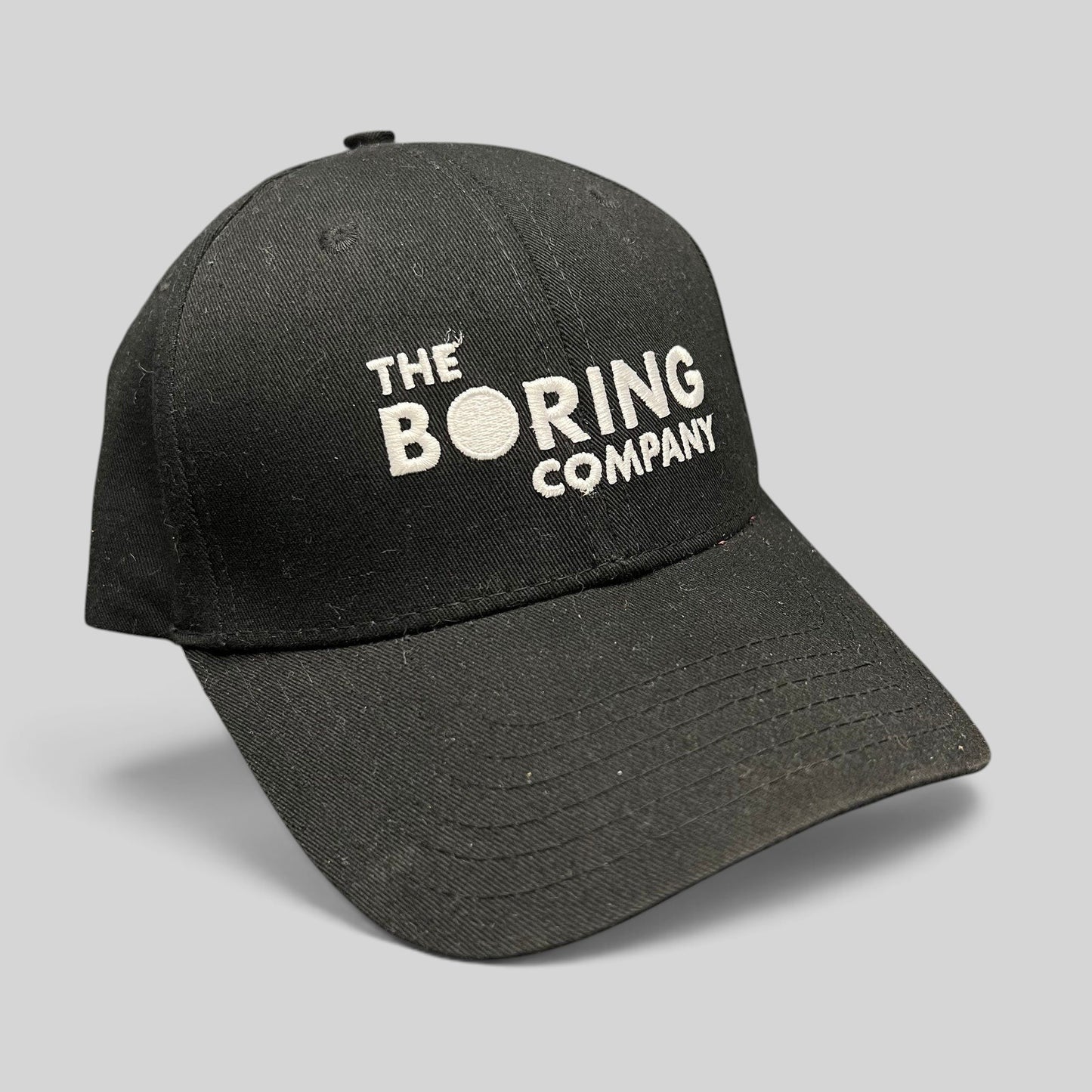 Raree Finds black The Boring Company strapback hat with white embroidered logo on a structured cotton crown