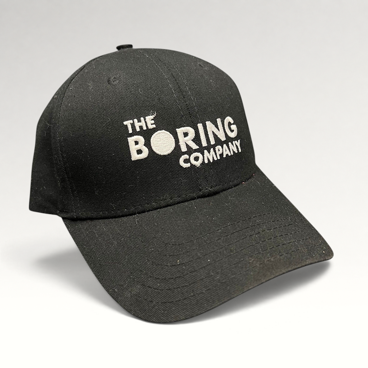 Raree Finds black The Boring Company strapback hat with white embroidered logo on a structured cotton crown