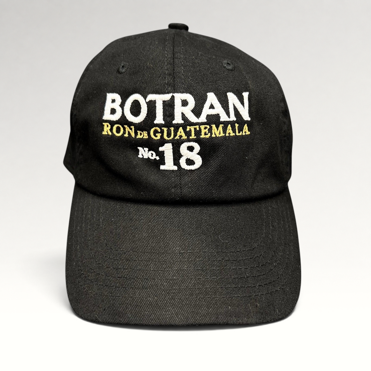 Raree Finds black cotton strapback hat featuring white and gold Botran Ron de Guatemala No. 18 embroidered logo