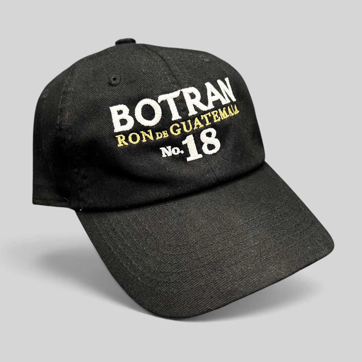 Raree Finds black cotton strapback hat with white and gold Botran Ron de Guatemala No. 18 embroidery on the front.