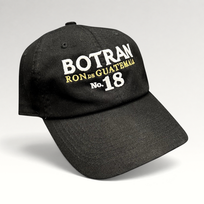 Raree Finds black cotton strapback hat with white and gold Botran Ron de Guatemala No. 18 embroidery on the front.