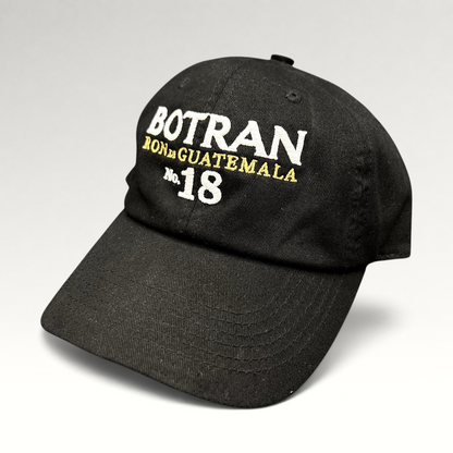Raree Finds black cotton strapback hat featuring white and gold Botran Ron De Guatemala No 18 embroidery