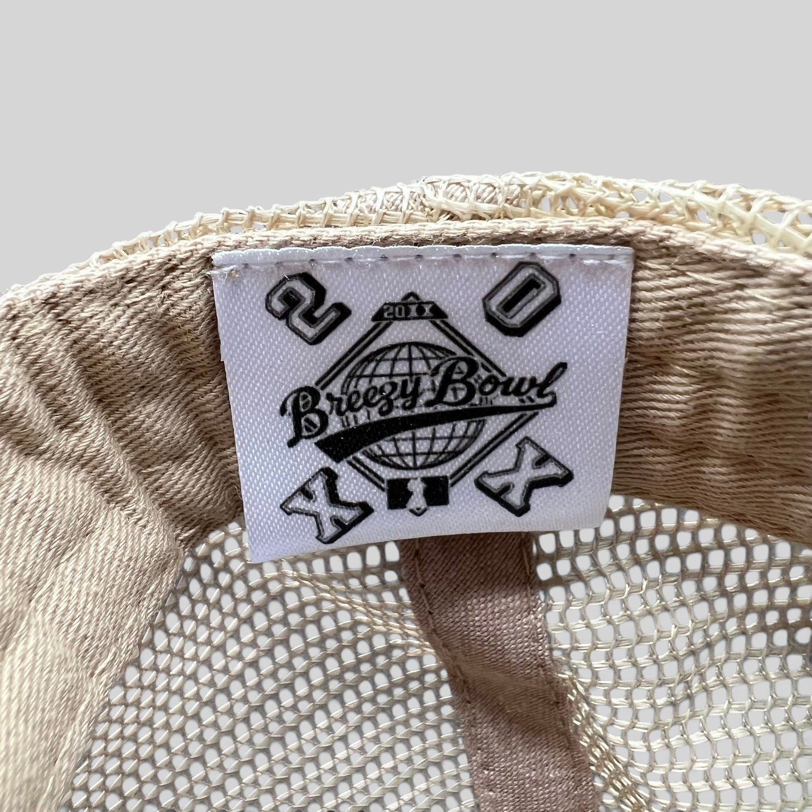 Raree Finds Breezy Bowl XX trucker hat interior label with globe logo and 20th anniversary branding on mesh fabric