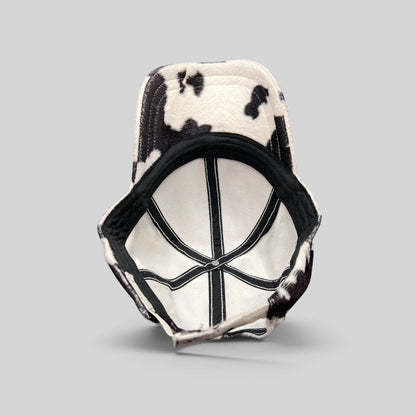 Raree Finds BULA black and white cow print plush fleece cap showing the interior lining and adjustable back strap.