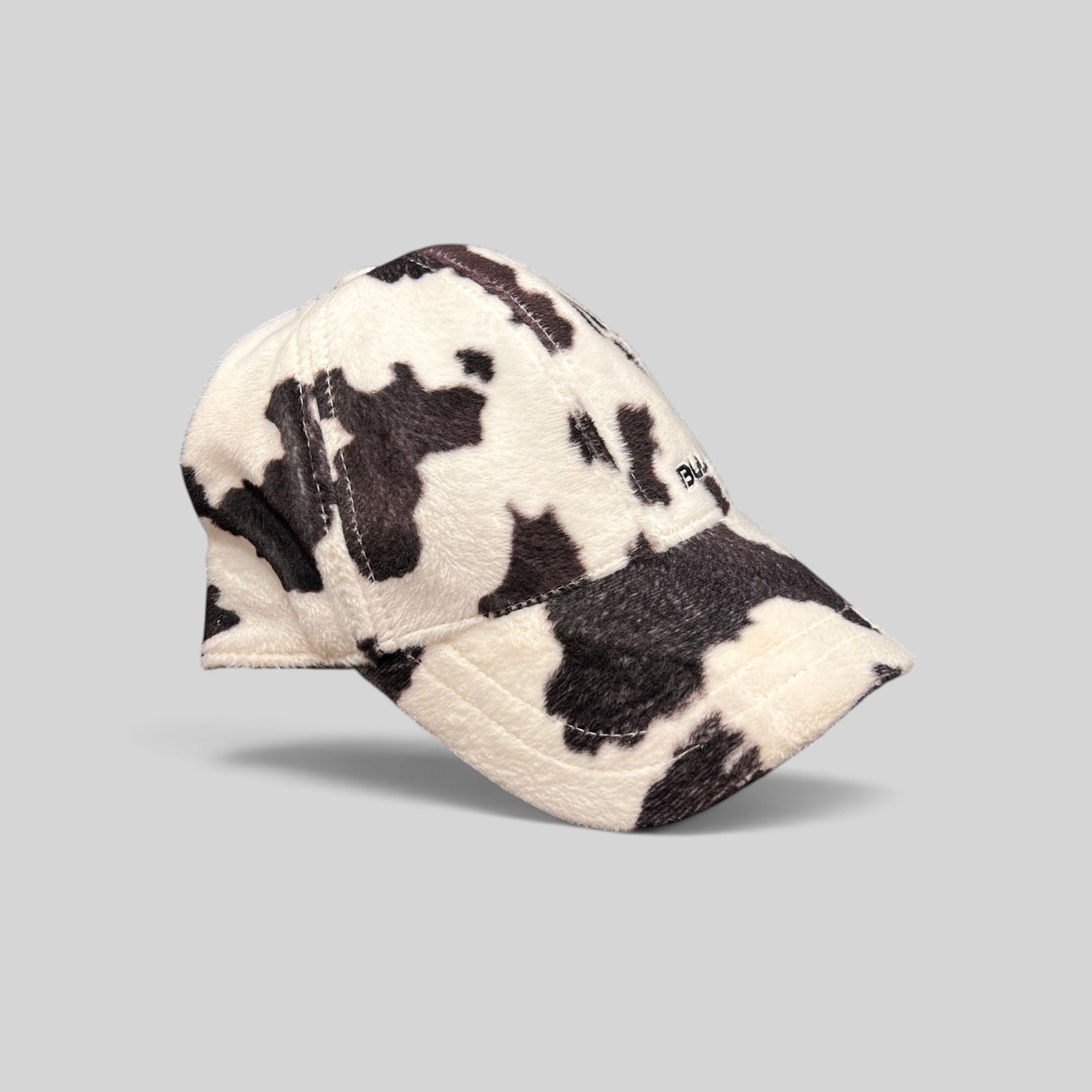 Raree Finds BULA black and white cow print plush fleece baseball cap with a curved brim and side embroidery.