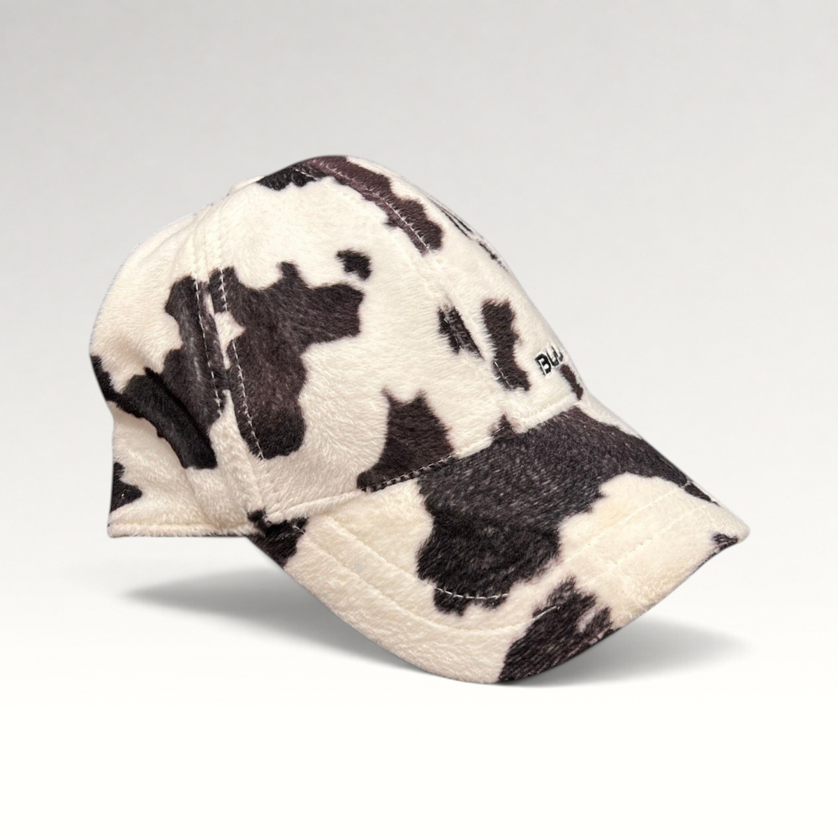 Raree Finds BULA black and white cow print plush fleece baseball cap with a curved brim and side embroidery.