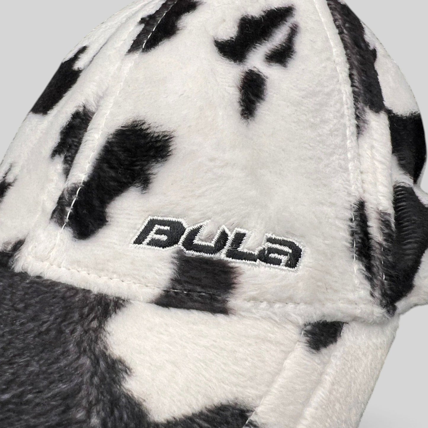 Raree Finds BULA black and white cow print plush fleece cap with embroidered side logo detail