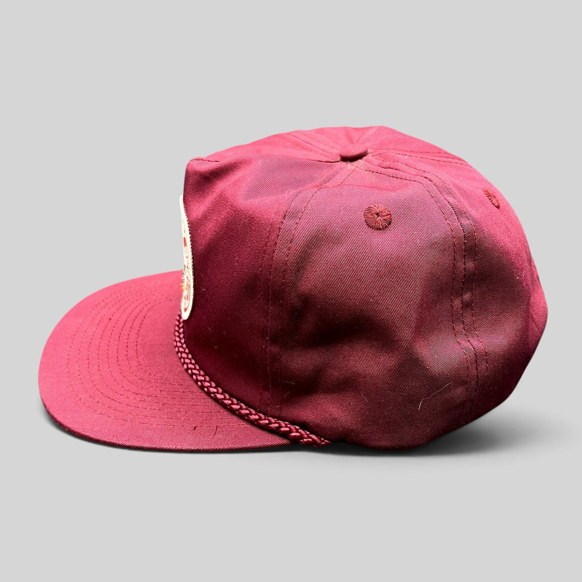 Raree Finds vintage burgundy trucker hat with braided rope detail and Rapid Delivery Service patch, side profile view.