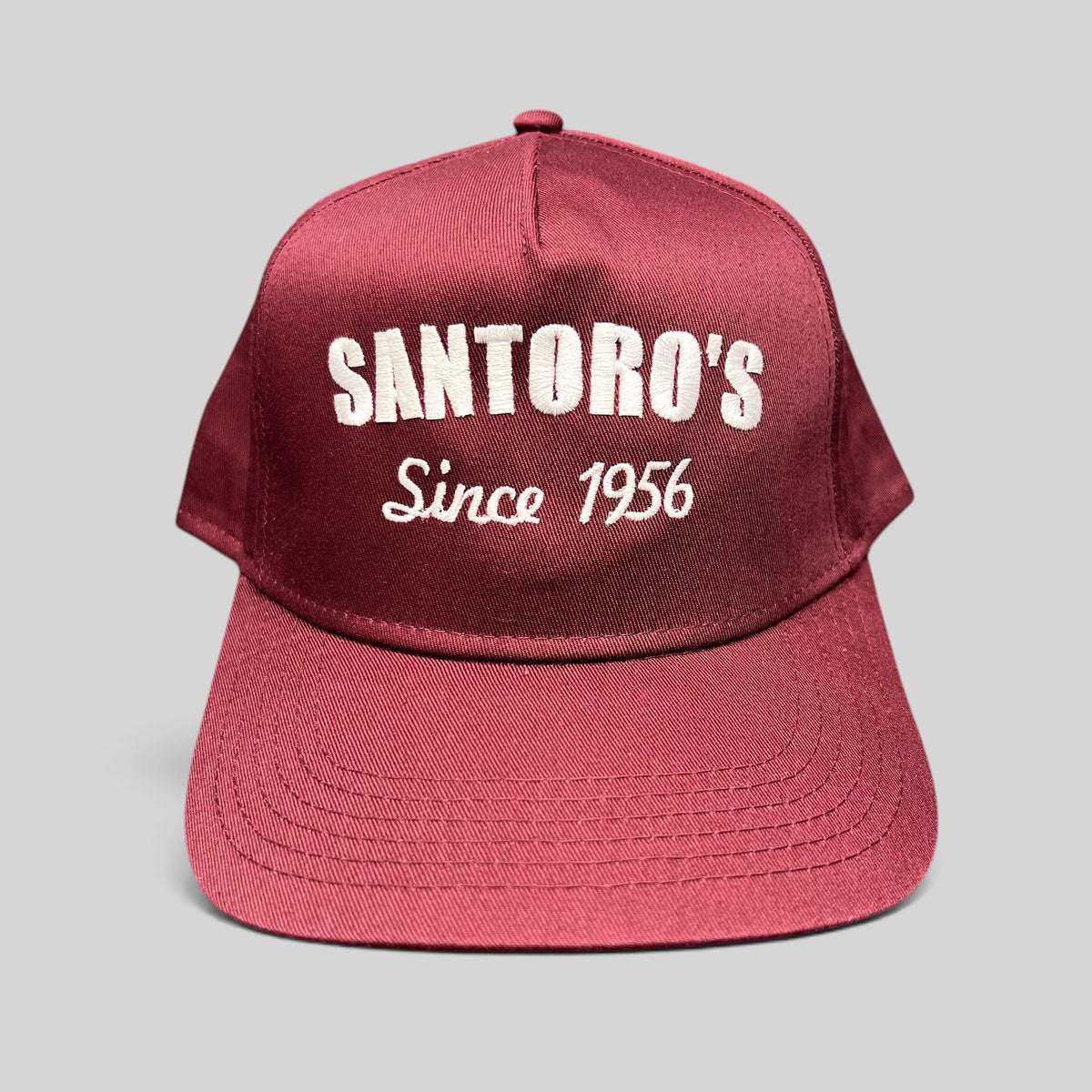 Raree Finds burgundy Otto Cap snapback hat with white Santoro’s Since 1956 embroidery and a structured flat brim.