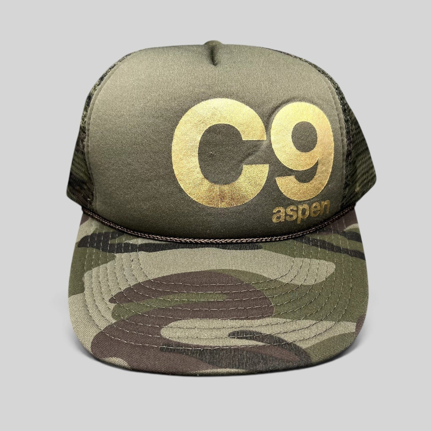 Raree Finds vintage Cloud 9 Aspen trucker hat with olive foam front, gold C9 logo, camo brim, and rope detail.