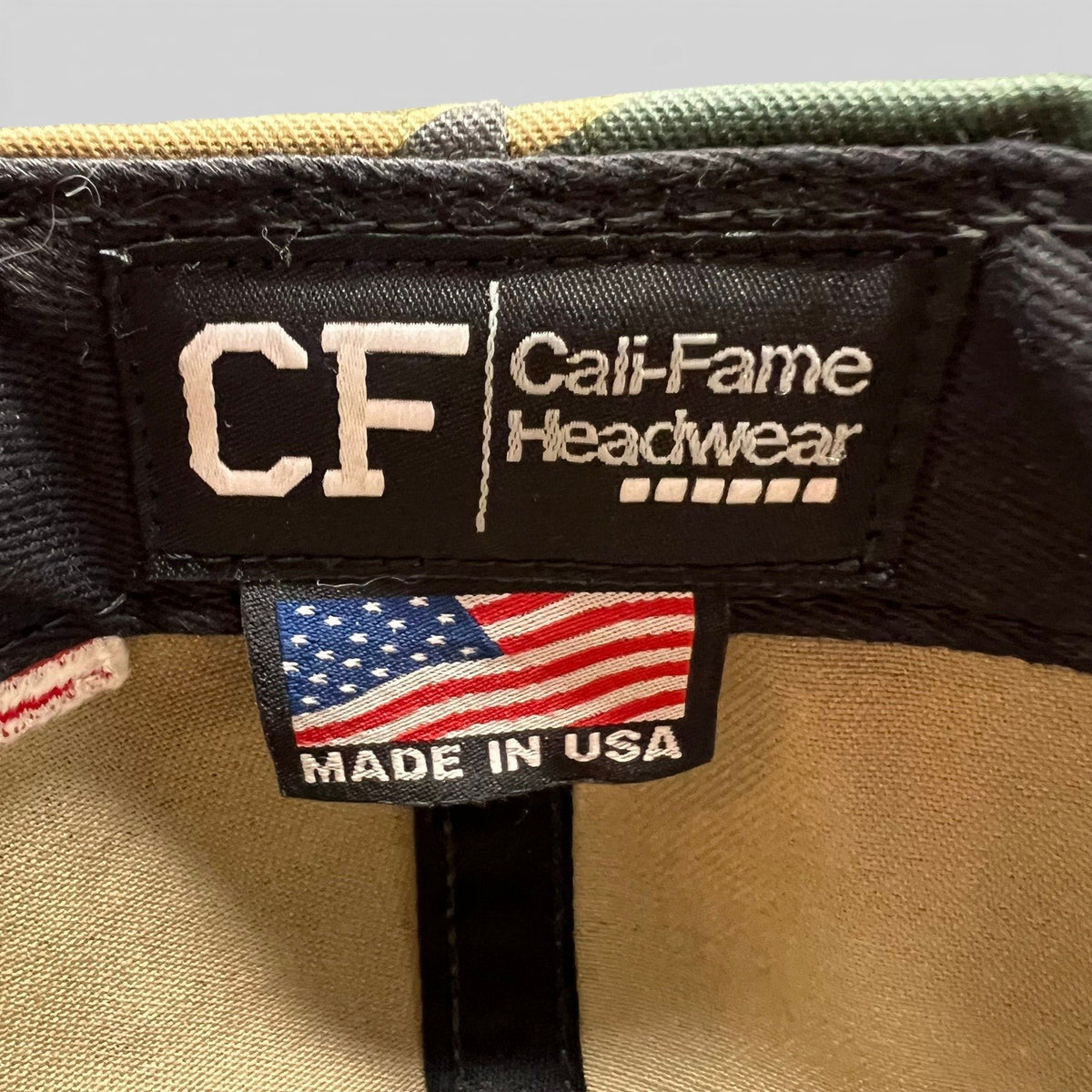 Raree Finds Cal Fame Headwear label inside a camo snapback hat with a Made in USA American flag tag