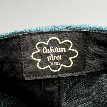 Raree Finds Calidum Aires interior black fabric brand label with white embroidered logo inside a teal suede hat