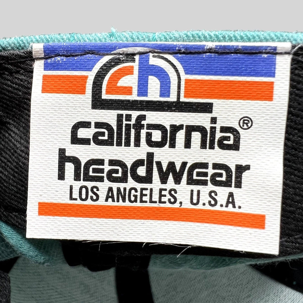 Raree Finds vintage California Headwear label with logo and Los Angeles USA text on a teal and gray snapback hat