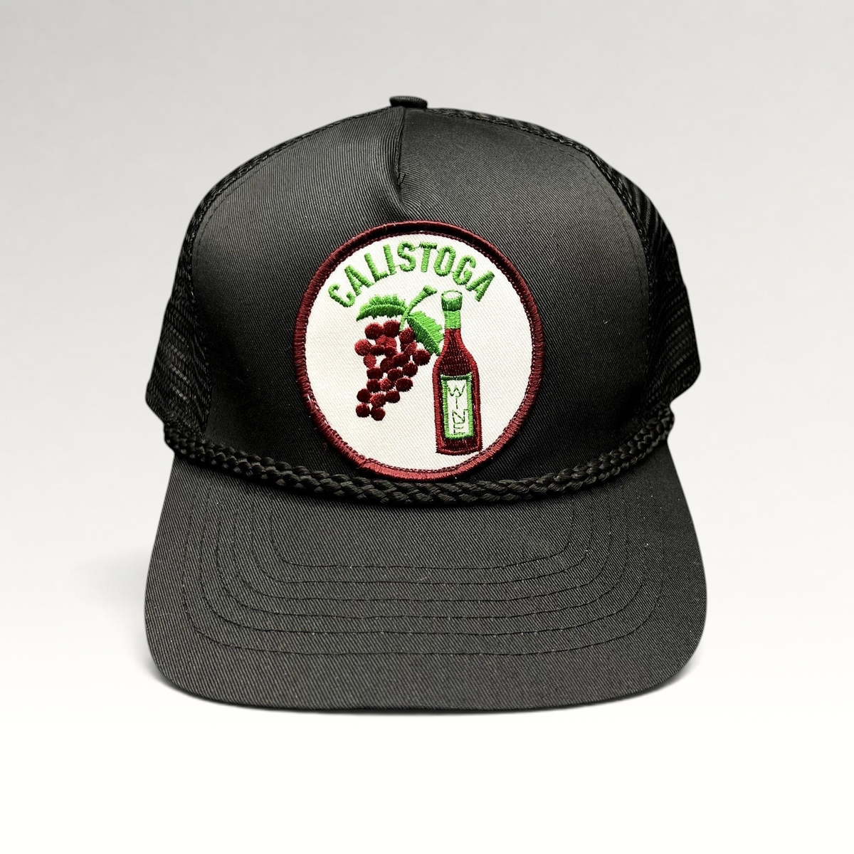 Raree Finds vintage black Calistoga Wine trucker hat with embroidered grape and wine bottle patch and braided rope