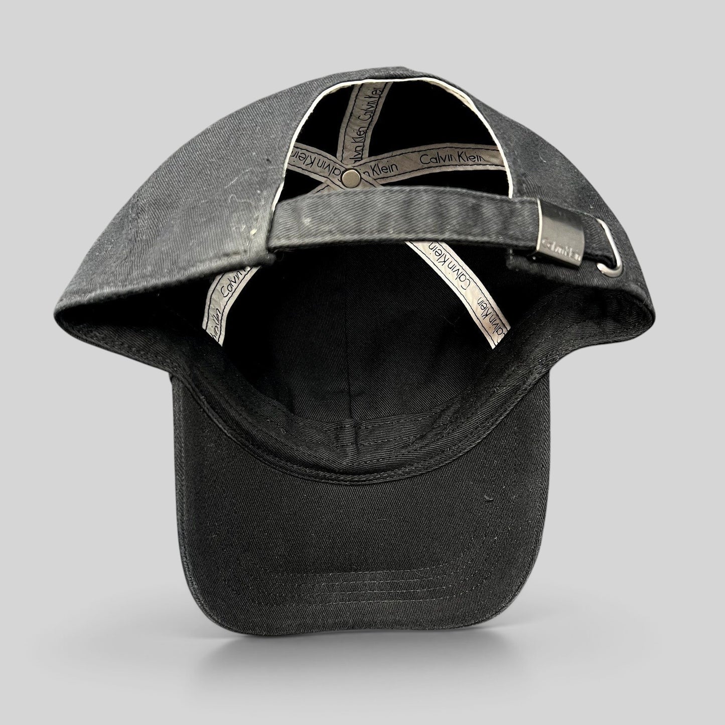 Raree Finds vintage black Calvin Klein strapback hat showing interior branded taping and metal buckle closure